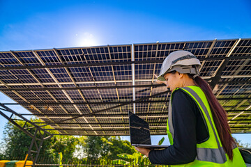Engineer in safety vest and helmet pointing towards a solar powered carport, illustrating...