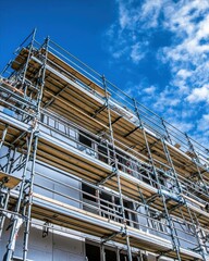 A construction site with scaffolding under a blue sky.