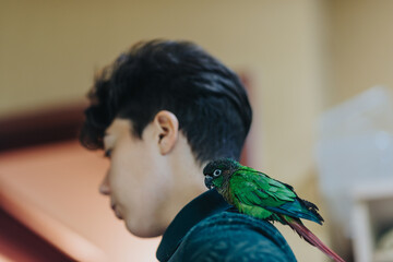 A girl with short hair gazes away as a vivid green parrot perches calmly on her shoulder, depicting a serene moment of companionship and nature.