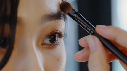 makeup artist using makeup brush for eyes and applying brown eyeshadow. make-up for young asian girl. Close-up