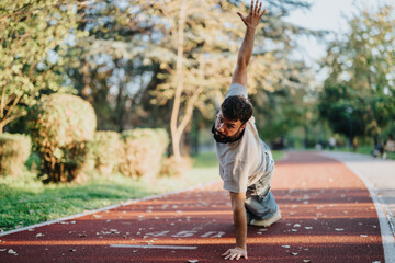 A man performs a yoga pose on a running track surrounded by nature. The image captures a moment of...