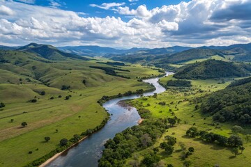 Naklejka premium an aerial view of a beautiful landscape with a river running through it. The river is surrounded by lush green hills and valleys, with patches of grass and trees scattered throughout.