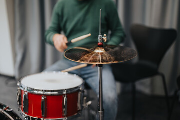 A drummer focuses on playing a cymbal during a practice session. The image captures the dynamics of...
