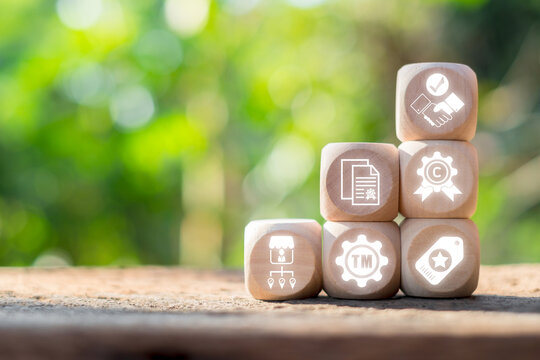 Wooden blocks with icons representing intangible assets like trademarks and copyrights, set against a blurred natural background.