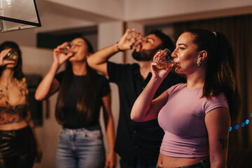 A lively group of friends celebrating a birthday at home, raising glasses in a joyful toast. The...