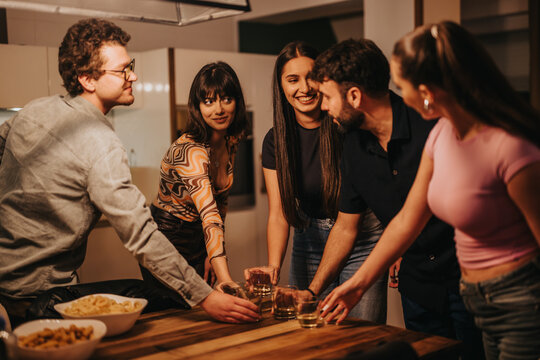 A group of friends gathers around a table, sharing drinks and laughter during a festive birthday celebration at home. The warm atmosphere highlights friendship and joy.