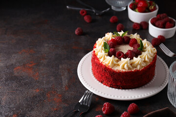 Red velvet cake on plate and bowls with berries on dark gray background, space for text