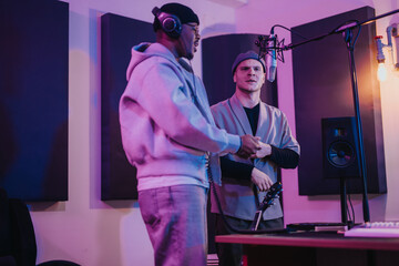 Two musicians collaborating in a modern recording studio with microphones and headphones