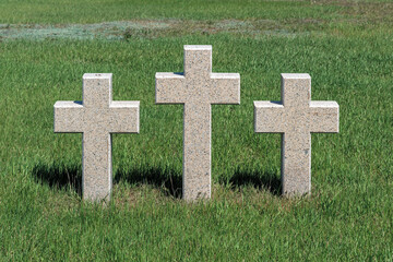 Three catholic stone crosses on young green grass at the German military cemetery in Rossoshki. Volgograd. Russia