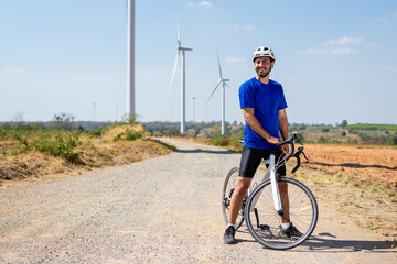 Caucasian man taking a break while riding bicycle at wind turbine field. 