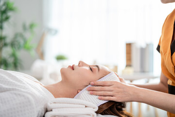 Asian young woman getting head and facial massage treatment at beauty spa.