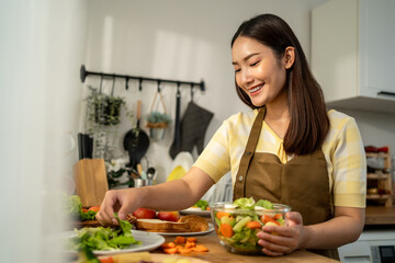 Asian young woman cooking healthy foods in kitchen in morning at home.