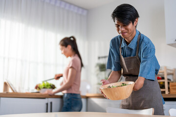 Asian young amputee without arm cooking foods with family in kitchen. 