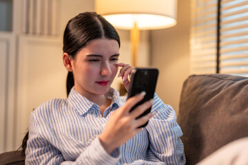 Exhausted Asian young woman hurt eye while using mobile phone at night. 