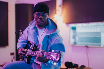 Obraz premium A musician is engrossed in creating music in a studio setting, surrounded by recording equipment and technology, highlighting creativity and passion in music production.