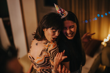 Two friends celebrate joyfully at a cozy home birthday party, embracing happiness and friendship. The atmosphere is warm and inviting, perfect for creating cherished memories together.