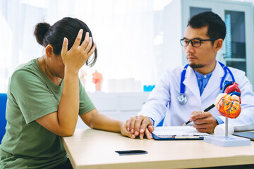 A woman with heart disease visits a doctor at the table in a hospital. The doctor explains conditions like coronary artery disease, arrhythmia,and heart valve disease,providing advice and medication