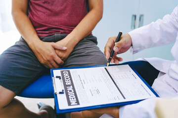 A man suffering from urinary tract infections visits a doctor at the examination table in a...
