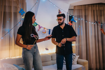 A cozy birthday celebration among friends in a living room, featuring party hats and decorations....