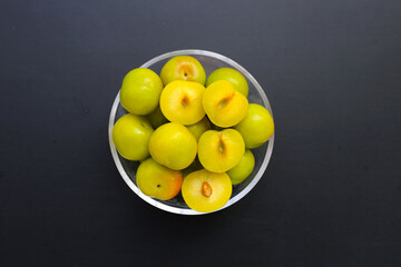 Fresh green plum fruit on dark background.