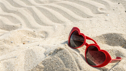 Fototapeta premium Heart shaped sunglasses resting on sandy beach, evoking summer vibes