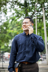 Smiling Asian Man In Formal Clothes Calling Using Smartphone While Looking Away
