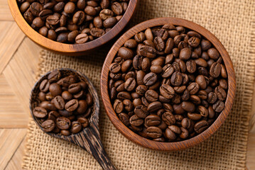 Roasted coffee beans in wooden bowl with spoon, Arabica coffee, Top view