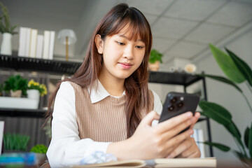 Student asian woman lying use smart phone in dorm room college mobile addict spending time checking news technology e-commerce.