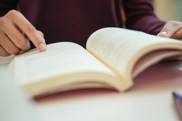 girl student reading book preparing for college exam Young female student studying and writing on notebook making  in school library.
