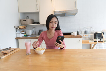 Asian woman eating while holding smartphone phone addiction concept