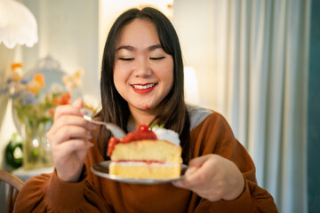 Beautiful Asian woman eating tasty cake. Teen girl eating the cake.