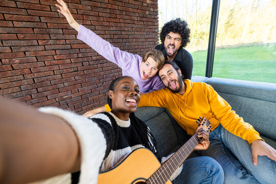 A diverse group of friends bonding and having fun indoors, making joyful memories playing guitar together - Powered by Adobe