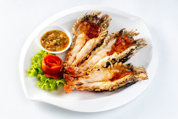 Grilled giant river prawn served on a plate with Thai seafood sauce. On a white background