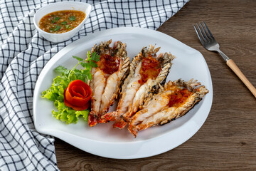 Grilled giant river prawn served on a plate with Thai seafood sauce. Thai cuisine.