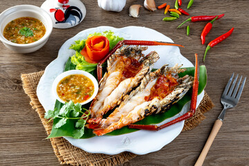 Grilled giant river prawn served on a plate with Thai seafood sauce. Thai cuisine.