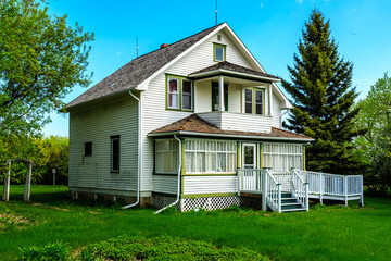 A large white house with a green roof sits in a grassy yard