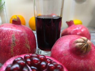 sweet red pomegranate on a wooden table next to a squeezed glass of juice