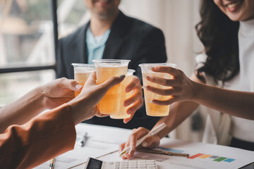 Business team toasting with beer in plastic cups after successful meeting, celebrating achievement and teamwork