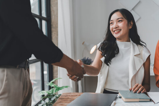 Business partners shaking hands in a modern office, celebrating the successful closing of a deal and solidifying their partnership