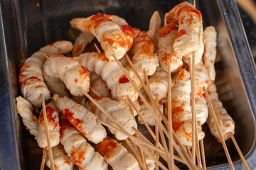 A line of street food shrimp tails or sunfish skewers, covered in crispy coating, displayed for sale. Popular frozen snack trend, viral in street food markets and perfect for quick fried treats.