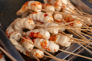 A line of street food shrimp tails or sunfish skewers, covered in crispy coating, displayed for sale. Popular frozen snack trend, viral in street food markets and perfect for quick fried treats.