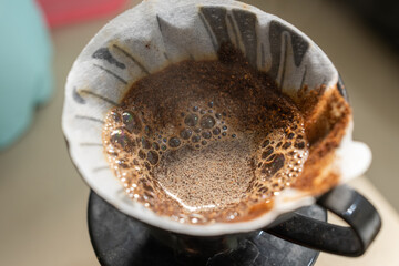 Close-up of coffee grounds blooming in a V60 dripper with bubbles forming during pour-over brewing. Captures fresh coffee extraction, manual brewing, and the aromatic V60 coffee-making process.