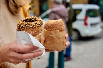 Tourist holds trdelnik against Prague street, Grilled rolled dough topped with sugar, Traditional Czech hot sweet pastry, street bakery in Prague