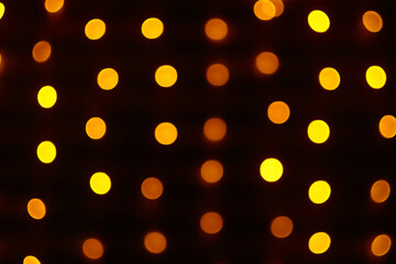 Warm glowing bokeh lights on dark background. Abstract holiday light effect for posters and headers.