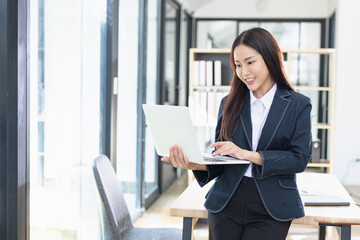 Asian businesswoman working on digital laptop standing in office, Businesswoman and Marketing...
