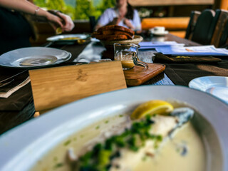 Fried Golden trout fish with lemon and herbs in a white plate on a wooden table at the restaurant in Ukraine