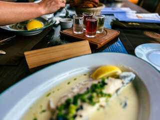 Fried Golden trout fish with lemon and herbs in a white plate on a wooden table at the restaurant in Ukraine