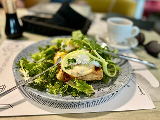 Green salad with poached egg on a toast and mozzarella cheese on a plate in restaurant.