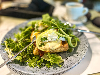 Green salad with poached egg on a toast and mozzarella cheese on a plate in restaurant.