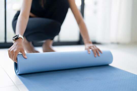 Woman preparing for yoga practice, rolls yoga mat